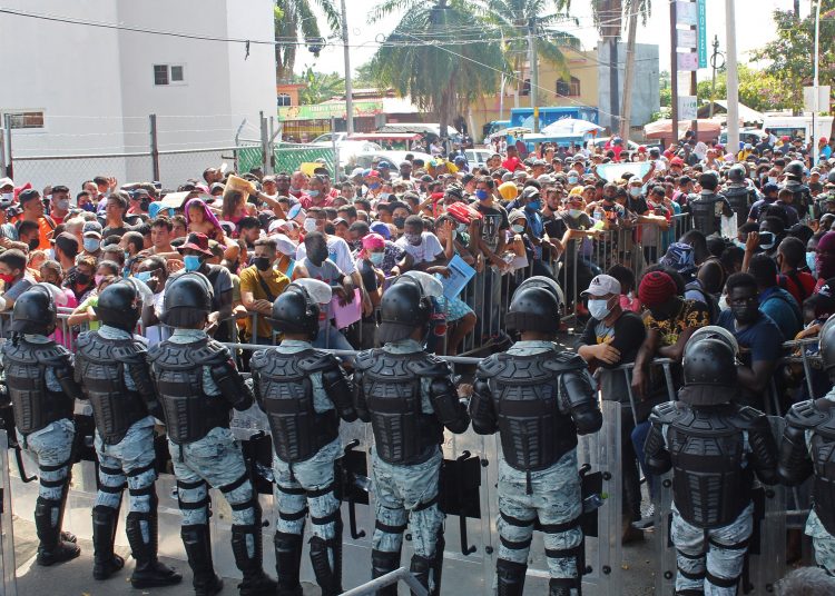 MEX5187. TAPACHULA (MÉXICO), 14/02/2022.- Migrantes protestan hoy en las oficinas de las oficinas del Instituto Nacional de Migración (INM), en la ciudad de Tapachula, en el estado de Chiapas (México). Fuertemente vigilados por miembros de la Guardia Nacional (GN), unos 800 migrantes marcharon este lunes desde el centro de la ciudad mexicana de Tapachula hacia las oficinas de la su delegación del Instituto Nacional de Migración (INM) para exigir documentos que regularicen su situación. EFE/ Juan Manuel Blanco