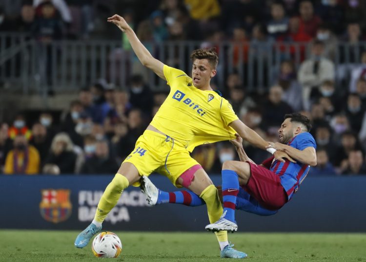 BARCELONA, 18/04/2022.- El delantero del Cádiz, Iván Alejo (i), intenta controlar el balón ante la falta del defensa del FC Barcelona, Jordi Alba, durante el encuentro correspondiente a la jornada 32 de primera división que disputan hoy lunes en el estadio del Camp Nou, en Barcelona. EFE / Andreu Dalmau.