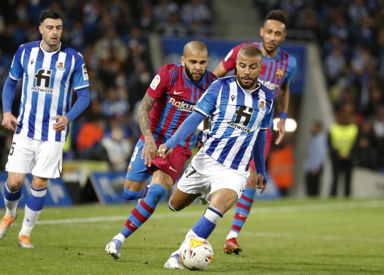 SAN SEBASTIÁN, 21/04/2022.- El centrocampista de la Real Sociedad, Rafinha Alcántara(d) juega un balón ante Dani Alves (c), del FC Barcelona, durante el partido de Liga en Primera División que disputan hoy jueves en el Reale Arena, en San Sebastián. EFE/Juan Herrero
