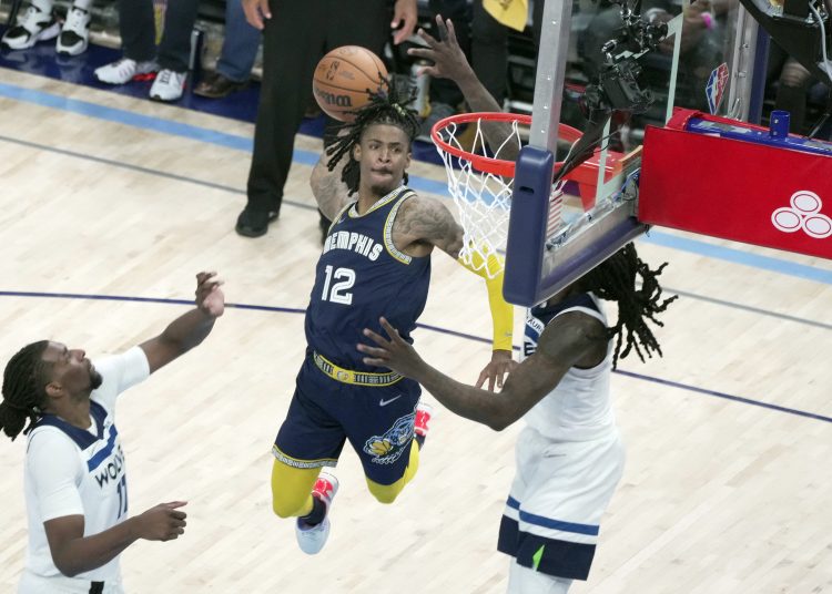 AME4358. MEMPHIS (ESTADOS UNIDOS), 26/04/2022.- Ja Morant (c) de los Memphis Grizzlies clava hoy el balón contra los Minnesota Timberwolves, durante un partido de la NBA en el FedEx Forum de Memphis, Tennessee (EEUU). EFE/ Karen Pulfer Focht