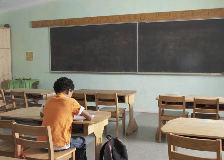 Mixed Race boy in empty classroom