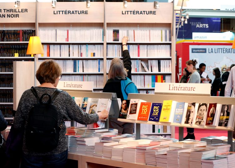 Visitors look at books displayed at the 2017 annual Paris book fair, France, March 24, 2017. REUTERS/Charles Platiau