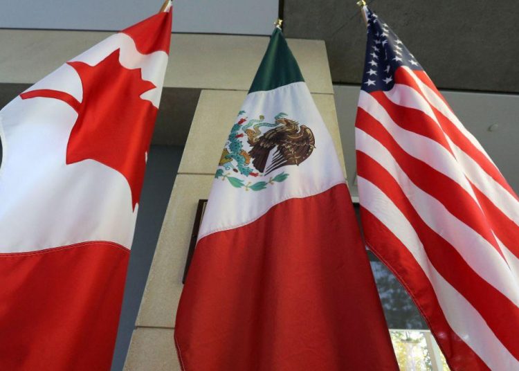 (FILES) In this file photo taken on September 24, 2017 the Mexican, US and the Canadian flags sit in the lobby where the third round of the NAFTA renegotiations are taking place in Ottawa, Ontario. - Canadian and US negotiators reached a deal late on September 30, 2018 on reforming the North American Free Trade Agreement (NAFTA), Canadian media reported. (Photo by Lars Hagberg / AFP)