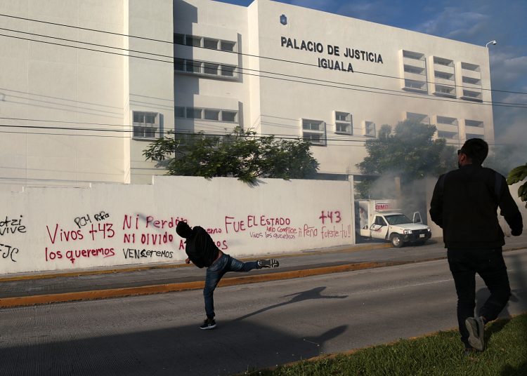 MEX5269. IGUALA (MÉXICO), 27/09/2022.- Manifestantes protestan para exigir justicia por los 43 desaparecidos de Ayotzinapa, hoy, en la entrada del Palacio de Justicia en Iguala, estado de Guerrero (México). Estudiantes mexicanos vandalizaron el Palacio de Justicia de la ciudad de Iguala, en el estado de Guerrero, sur de México, e incendiaron dos vehículos de empresas particulares al concluir su jornada de protestas por el octavo aniversario de la desaparición de los 43 estudiantes de Ayotzinapa ocurrida el 26 y 27 de septiembre de 2014. EFE/ Jose Luis de la Cruz
