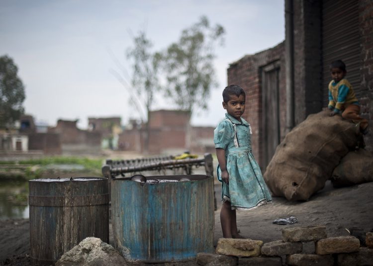 Children plays outside a metal polishing work-shop in the Shivnagar Mohalla slum in Moradabad district in Uttar Pradesh.