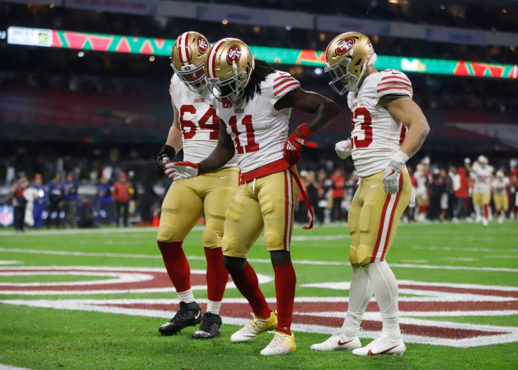 MEX487. CIUDAD DE MÉXICO (MÉXICO), 21/11/2022.- (i-d) Jake Brendel, Brandon Aiyuk y Christian McCaffrey de los San Francisco 49ers celebran hoy un touchdown contra los Arizona Cardinals, durante un juego por la semana 11 de la NFL en el Estadio Azteca en Ciudad de México (México). EFE/Isaac Esquivel