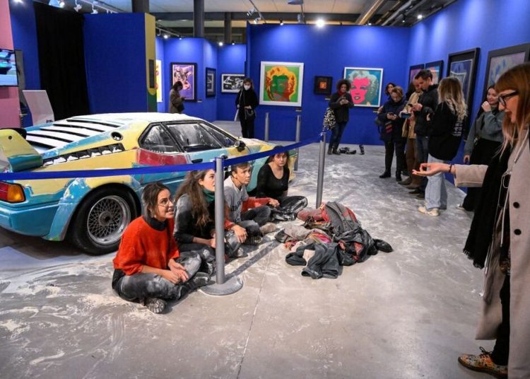 Climate activists of ''Ultima Generazione (Last Generation)" sit in front of an exibit after throwing flour on Andy Warhol's work, in Milan, Italy, November 18, 2022. REUTERS/Flavio Lo Scalzo