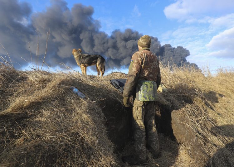 FEBRERO (9/10).- Un miliciano ucraniano y su perro observan la columna de humo procedente de un depósito petrolífero atacado por misiles rusos en las proximidades de Kiev, en Ucrania, el 27 de febrero. EFE/Alisa Yakubovych