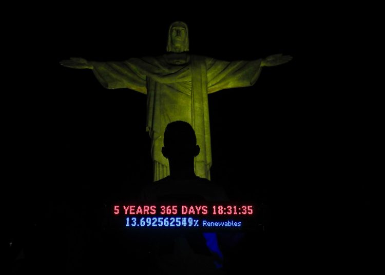 AME4963. RÍO DE JANEIRO (BRASIL), 22/07/2023.- Un voluntario sostiene una réplica del Reloj Climático frente al Cristo Redentor, durante una iniciativa internacional que señala el tiempo que queda para poder detener el calentamiento global y que por primera vez marcó menos de seis años, hoy, en Río de Janeiro (Brasil). Sobre el monumento más icónico de Brasil el reloj pasó de los 6 años, 0 días y 00:00:00 horas a los 5 años, 364 días y 23:59:59 horas, en un momento en que varios puntos del planeta registran un calor extremo. Ese es el tiempo que le resta a la humanidad "para mantenerse a salvo de escenarios climáticos catastróficos" y evitar traspasar el objetivo de limitar el calentamiento a 1,5 grados, según los organizadores de la acción. EFE/ André Coelho