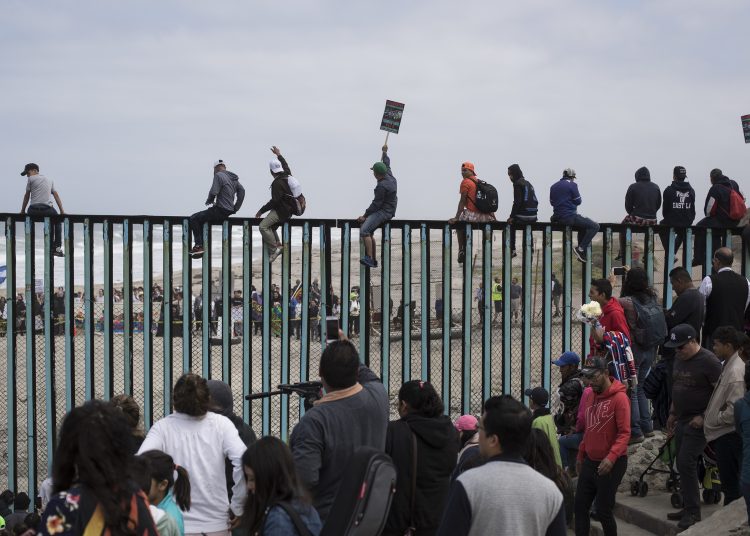 Central American migrants traveling with a caravan gather at the border wall, some sitting on top of it, look toward the U.S. from Mexico during a gathering of migrants living on both sides of the border, on the beach where the border wall ends in the ocean, in Tijuana, Mexico, Sunday, April 29, 2018. U.S. immigration lawyers are telling Central Americans in a caravan of asylum-seekers that traveled through Mexico to the border with San Diego that they face possible separation from their children and detention for many months. They say they want to prepare them for the worst possible outcome. (AP Photo/Hans-Maximo Musielik)