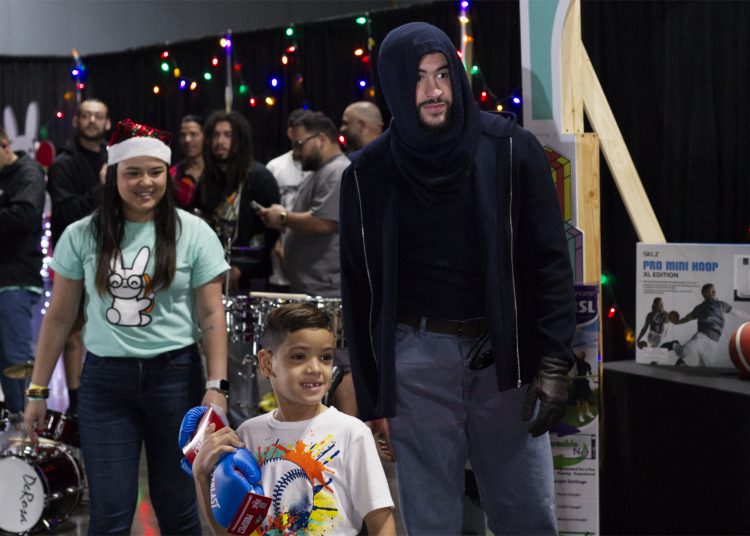 AME6099. SAN JUAN (PUERTO RICO), 23/12/2023.- El cantante Bad Bunny entrega regalos hoy, en el centro de convenciones, en San Juan (Puerto Rico). El artista puertorriqueño Bad Bunny entregó este sábado por cuarta ocasión, junto a su Fundación Good Bunny, artículos e instrumentos de música, deporte y pintura a miles de niños y jóvenes de Puerto Rico, como parte de las festividades navideñas. EFE/Thais Llorca
