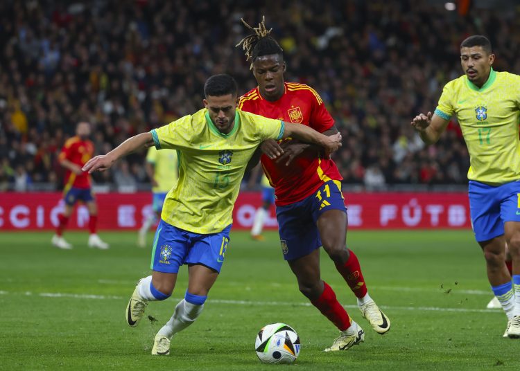 MADRID, 26/03/2024.- El defensa de la selección brasileña Yan Couto (i) lucha con Nicholas Williams, de la selección española, durante el partido amistoso que las selecciones nacionales de fútbol de España y Brasil disputan hoy martes en el estadio Santiago Bernabéu, en Madrid. EFE/Kiko Huesca