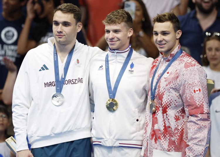 Paris (France), 31/07/2024.- (L-R) Silver medalist Kristof Milak of Hungary, gold medalist Leon Marchand of France, and bronze medalist Ilya Kharun of Canada pose on the podium for the Men 200m Butterfly final of the Swimming competitions in the Paris 2024 Olympic Games, at the Paris La Defense Arena in Paris, France, 31 July 2024. (200 metros, Francia, Hungría) EFE/EPA/FRANCK ROBICHON