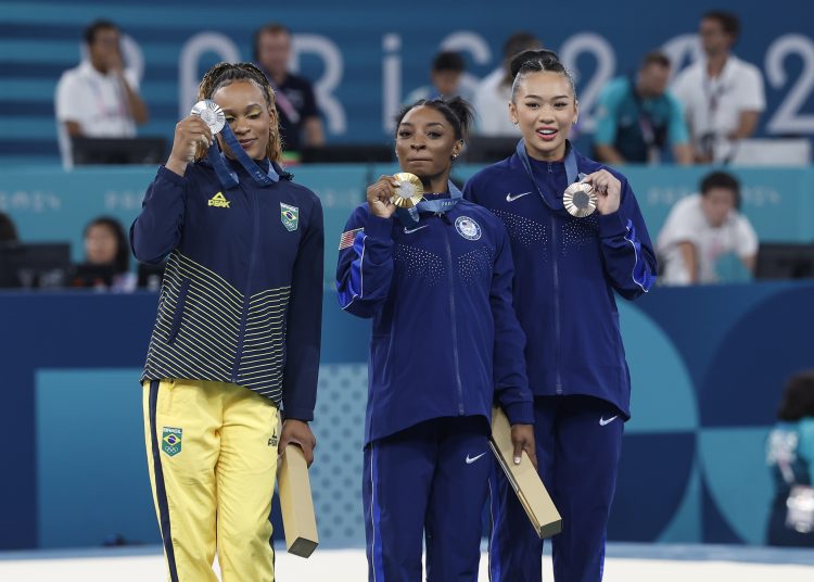 PARÍS, 01/08/2024.- Las estadounidenses Simone Biles (c) medala de oro; Sunisa Lee (d), bronce, y la brasileña Rebeca Andrade, medalla de plata, ene l podio tras la final de Concurso Completo Femenino de Gimnasia Artística, parte de los Juegos Olímpicos de París 2024 , en el Bercy Arena de la capital francesa. EFE/ Miguel Toña