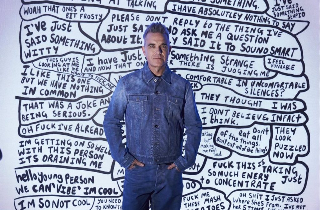 El cantante Robbie Williams posa al frente de un mural en el MOCO Museum