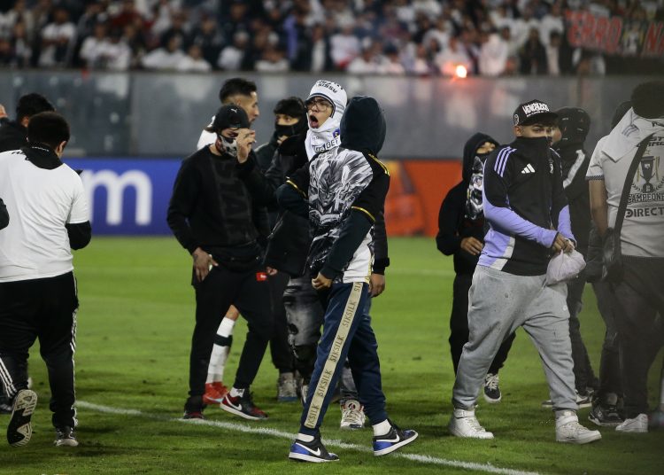 AME8108. SANTIAGO (CHILE), 10/04/2025.- Aficionados de Colo Colo invaden el campo de juego después de la muerte de dos hinchas asfixiados por una avalancha tras una carga policial este jueves, en un partido de la fase de grupos de la Copa Libertadores entre Colo Colo y Fortaleza en el estadio Monumental David Arellano, en Santiago (Chile). EFE/ Osvaldo Villarroel