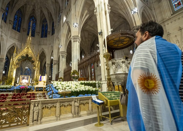 AME997. NUEVA YORK (ESTADOS UNIDOS), 21/04/2025.- Un hombre con la bandera de Argentina observa una imagen del Papa Francisco durante un homenaje este lunes, en la catedral de San Patricio en New York (Estados Unidos). EFE/ Angel Colmenares