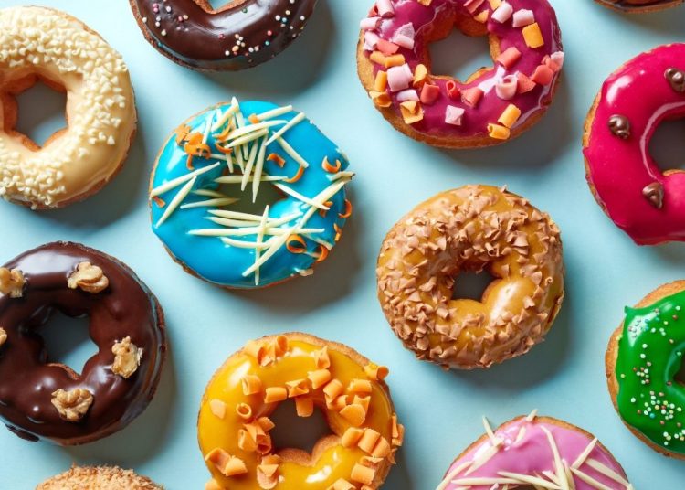 Various colorful donuts on blue background, top view
