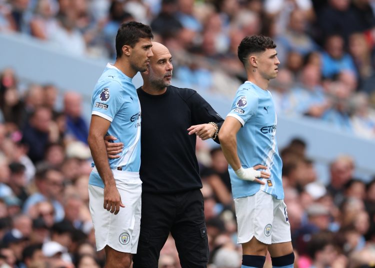 Manchester City manager Pep Guardiola speaks to Rodri of Manchester City