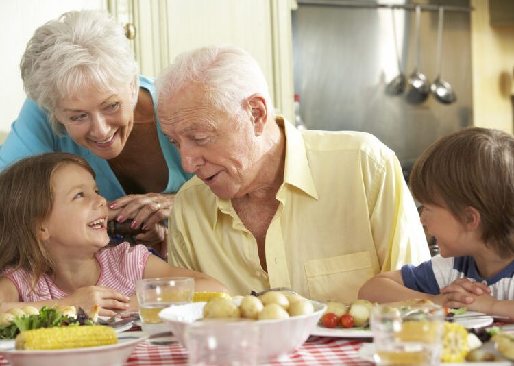 Grandparents And Grandchildren Eating Meal Together In Kitchen