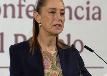 Policía y armas decomisadas, con banderas de México y Estados Unidos de fondo.