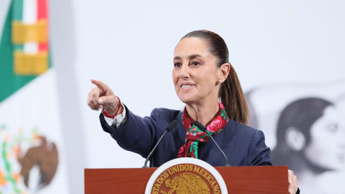Claudia Sheinbaum, presidenta de México, alza la mano durante un evento oficial mientras se dirige a los medios de comunicación en el Palacio Nacional.