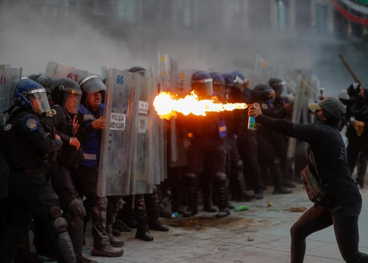 MEX4476. CIUDAD DE MÉXICO (MÉXICO), 02/10/2025.- Policías son agredidos este jueves, durante una manifestación por los 57 años de la matanza de Tlatelolco del 2 de octubre de 1968, en la Ciudad de México (México). Centenares de vándalos autonombrados "anarquistas" embozados encabezaron este jueves las acciones violentas, entre ellas ataques a la policía, en el Zócalo de la Ciudad de México, para opacar el mitin conmemorativo por el 57 aniversario de la masacre estudiantil de Tlatelolco del 2 de octubre de 1968. EFE/ Isaac Esquivel