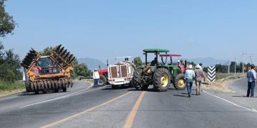 Productores de maíz retirando tractores de bloqueos carreteros en Michoacán.
