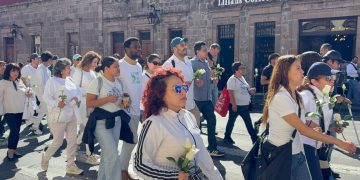 Manifestantes con rosas blancas en la fuente de Las Tarascas, Morelia, pidiendo justicia por familia de intérpretes