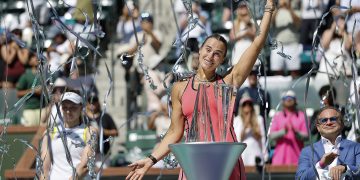 Aryna Sabalenka of Belarus poses with her Champions trophy as streamers fall after winning