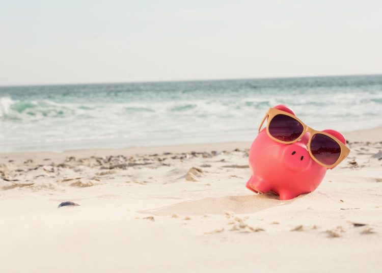 Piggy bank with sunglasses kept on sand at beach