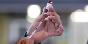 Personal médico aplicando vacunas para cortar la transmisión del sarampión entre menores y adultos