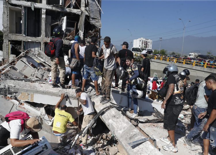 AME7645. CALI (COLOMBIA), 10/08/2026.- Personas caminan sobre los escombros de un edificio colapsado este lunes, en Cali (Colombia). Al menos 20 edificios sufrieron graves daños por consecuencia del terremoto de magnitud 7,4 que sacudió la mayor parte del país, con epicentro en la zona del Pacífico. EFE/ Ernesto Guzmán