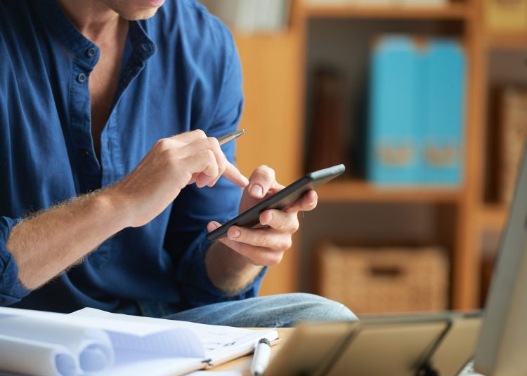 Hands of businessman with pen in his hand texting